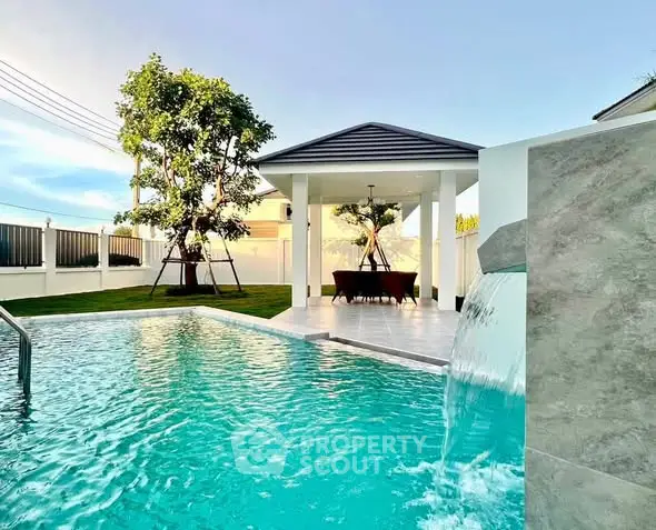 Luxurious outdoor pool with waterfall feature and covered seating area in modern backyard.
