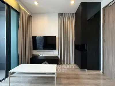 Modern living room with sleek black cabinetry and wall-mounted TV, featuring floor-to-ceiling curtains and a minimalist coffee table.