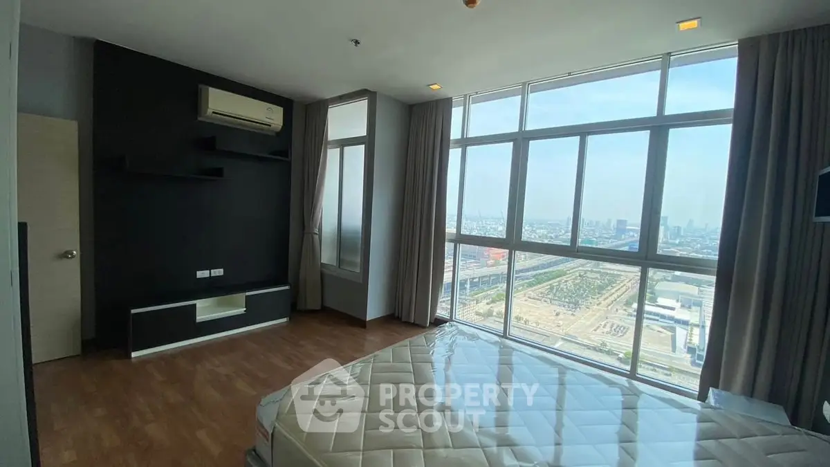 Spacious bedroom with large windows offering stunning city views.