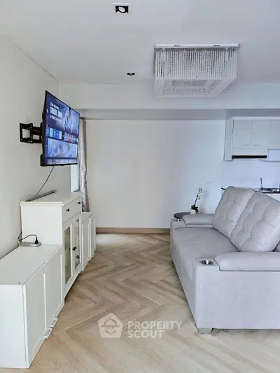 Modern living room with sleek design, featuring a mounted TV and stylish furniture, perfect for relaxation.