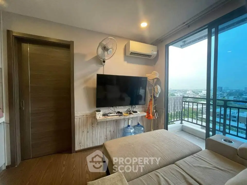 Modern living room with balcony view, featuring sleek TV setup and cozy seating area.