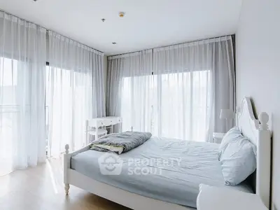 Bright and airy bedroom with large windows and elegant white furnishings.