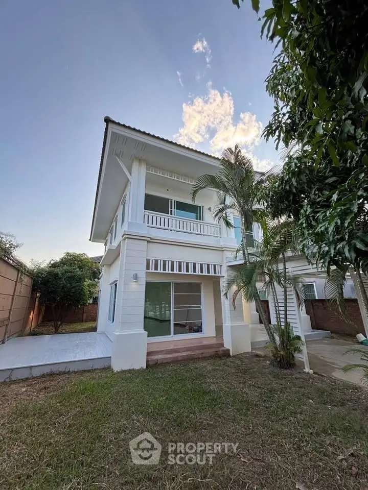Charming two-story white house with lush garden and spacious balcony, perfect for family living.