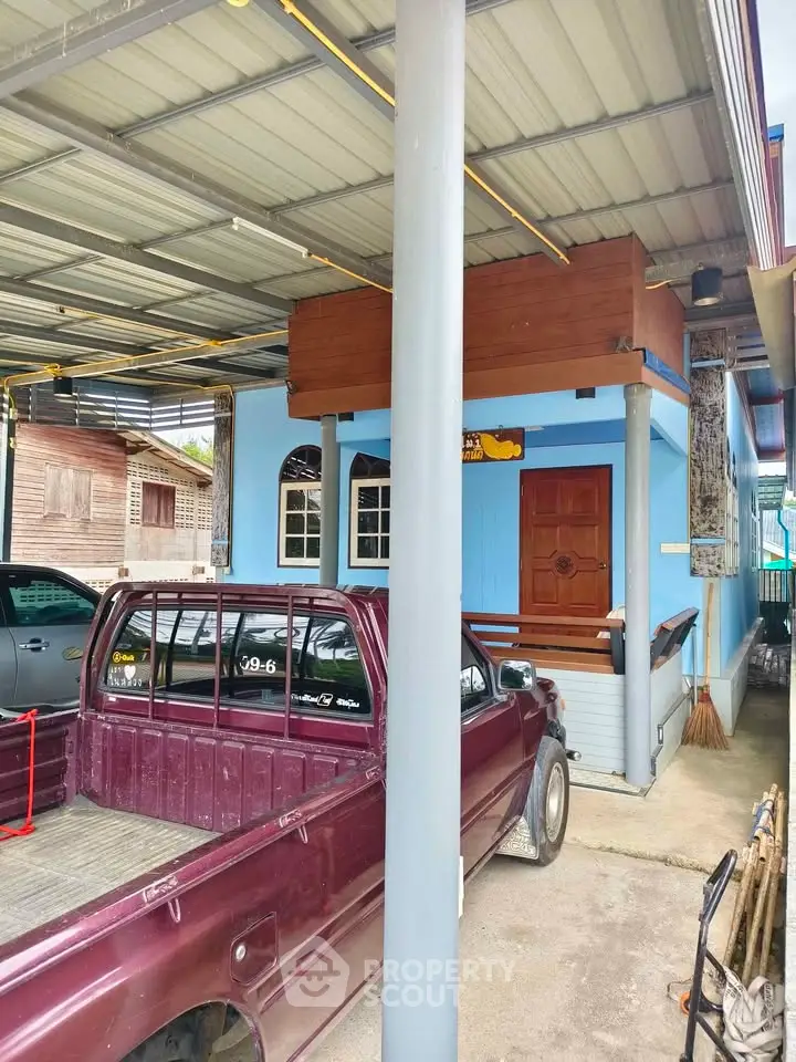 Charming blue house with covered parking and rustic wooden accents, perfect for cozy living.