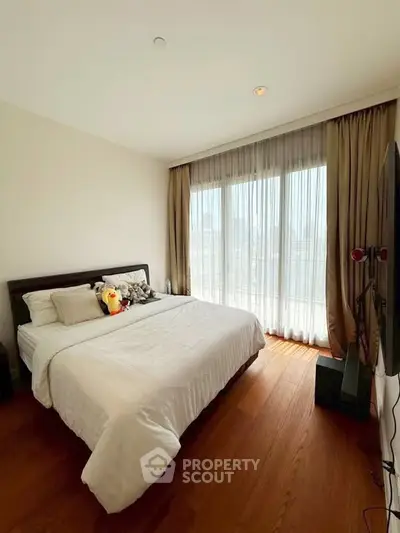 Spacious bedroom with large window and wooden flooring, perfect for natural light lovers.
