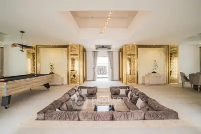 Luxurious living room with sunken seating and pool table, featuring elegant gold accents and modern lighting.