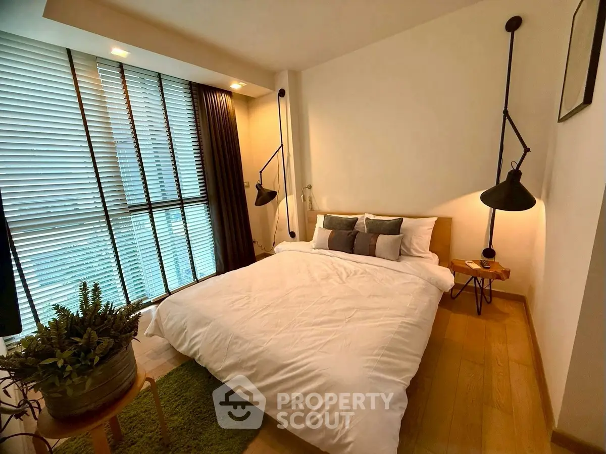 Cozy bedroom with modern lighting and large window for natural light