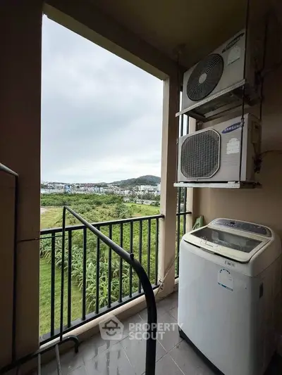 Charming balcony with lush green view and modern appliances, perfect for relaxation.