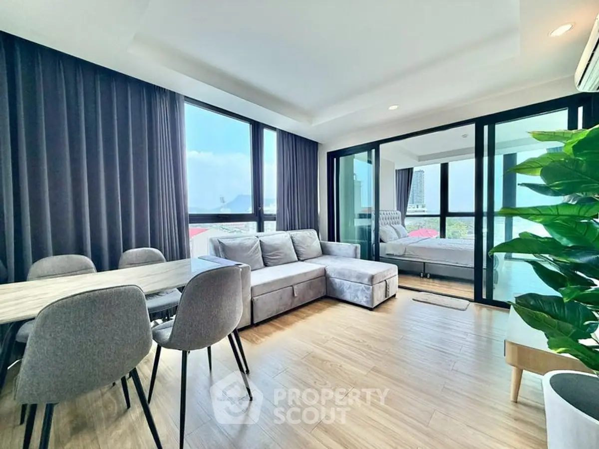 Modern living room with large windows and stylish furniture in a high-rise apartment.