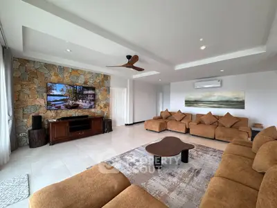 Spacious living room with modern decor and stone accent wall, featuring plush seating and a stylish ceiling fan.