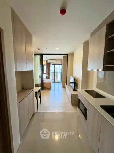 Modern open-layout kitchen leading to a bright living area with balcony view.