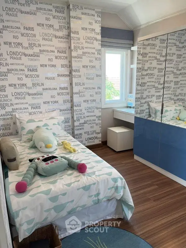 Charming children's bedroom with city-themed wallpaper and cozy decor.