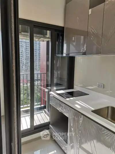Modern kitchen with sleek cabinetry and balcony view in urban apartment.
