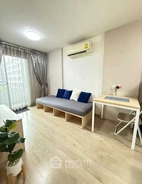 Modern living room with sleek design, featuring a cozy sofa, air conditioning, and natural light from large windows.
