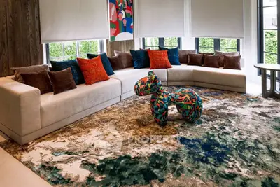 Luxurious living room with modern decor and vibrant accents, featuring a unique designer chair and plush seating.