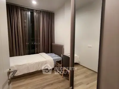 Cozy bedroom with modern furnishings and large window offering city views.