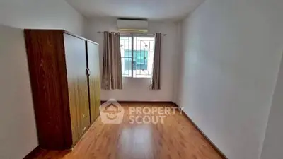 Spacious empty room with wooden flooring and large window, perfect for customization.