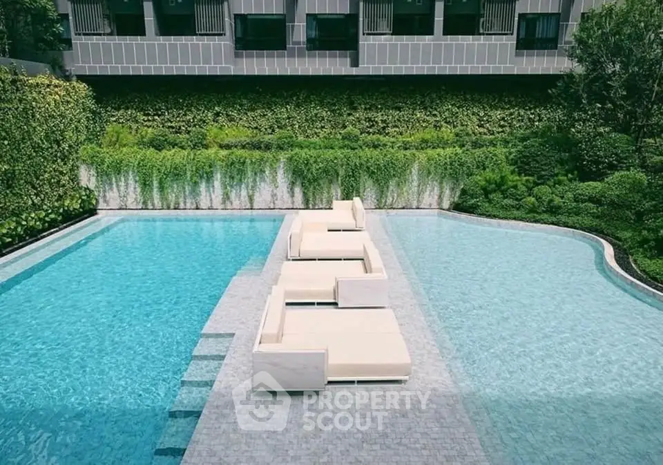Luxurious outdoor pool area with modern lounge chairs and lush greenery, perfect for relaxation and leisure.