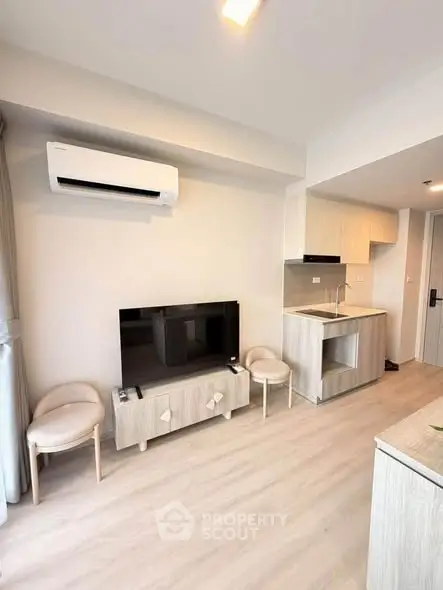 Modern living room with air conditioning and compact kitchen in a stylish apartment.