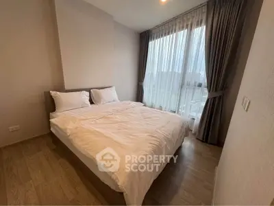 Cozy bedroom with large window and elegant curtains, featuring a comfortable double bed and wooden flooring.