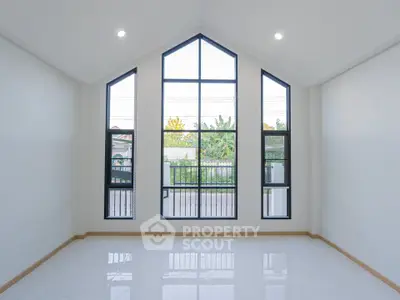 Spacious room with large windows and high ceiling, offering abundant natural light and modern design.