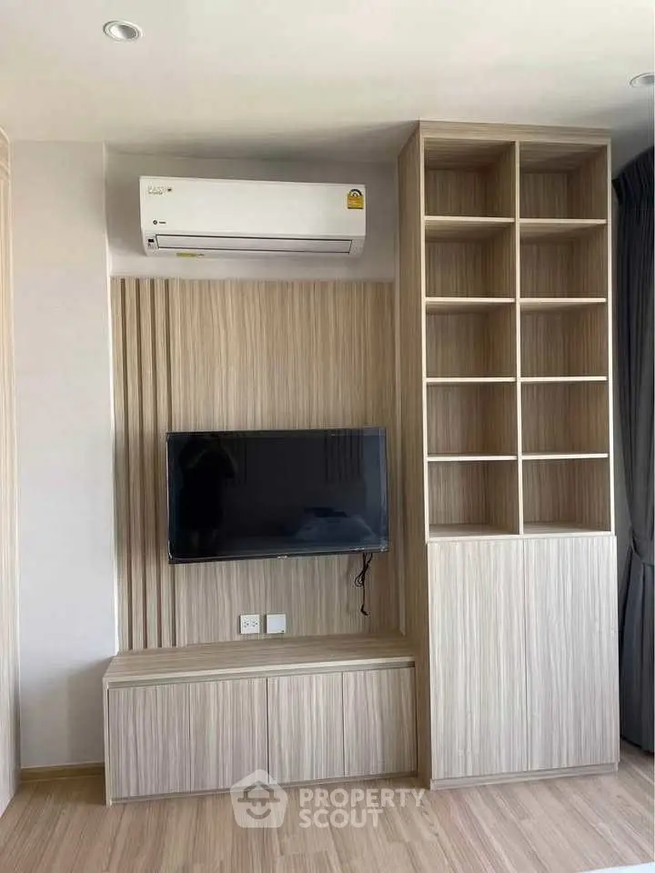 Modern living room with built-in TV unit and air conditioning, featuring sleek wooden cabinetry.