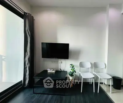 Modern living room with sleek black flooring, wall-mounted TV, and large window for natural light.
