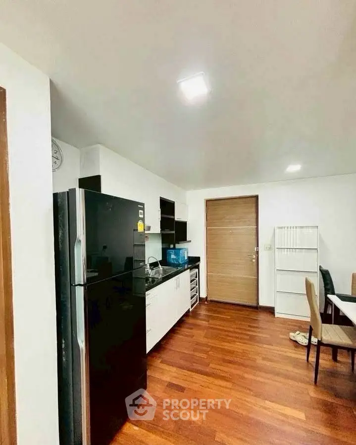 Modern kitchen with sleek black fridge and wooden flooring