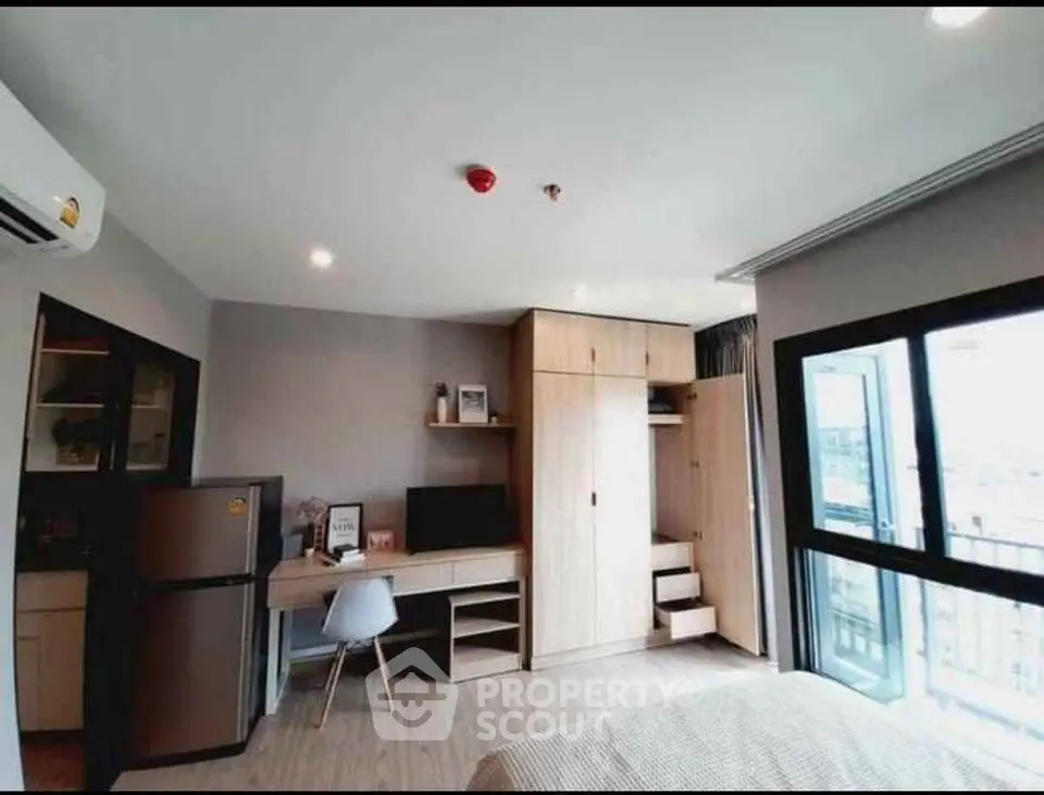 Modern bedroom with workspace and balcony view in urban apartment