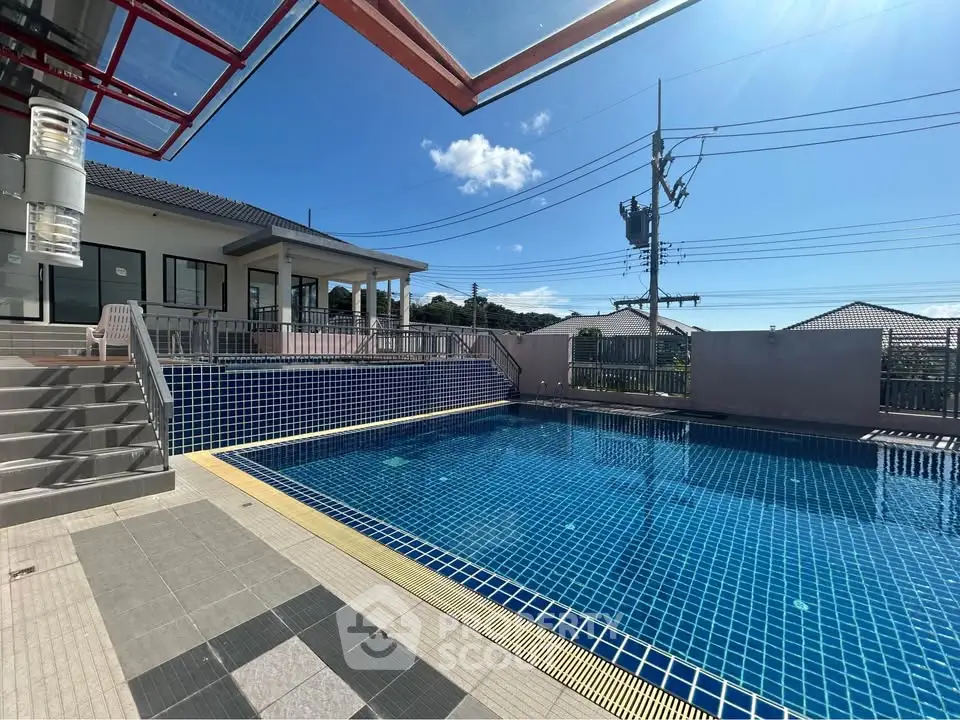 Stunning outdoor pool area with modern tiles and clear blue water under a bright sky.
