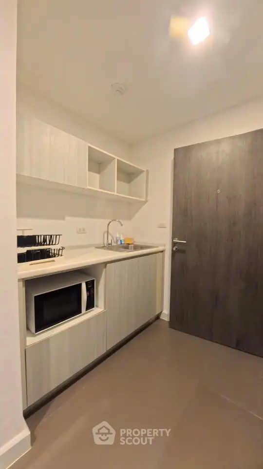 Modern compact kitchen with microwave and sleek cabinetry in a stylish apartment.