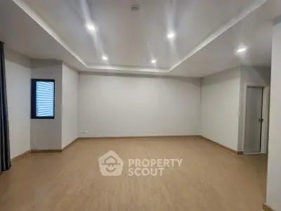 Spacious empty room with modern recessed lighting and wooden flooring
