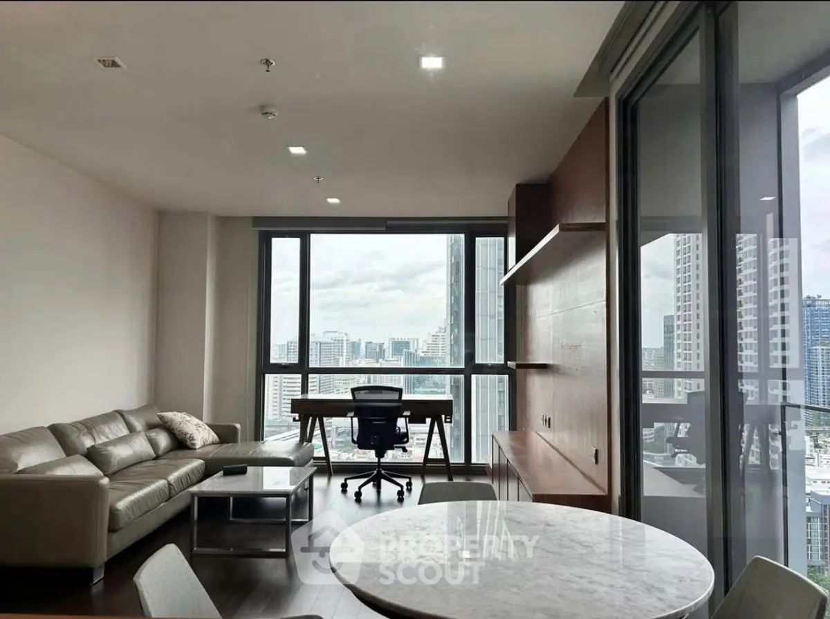Modern living room with city view, featuring sleek furniture and large windows.