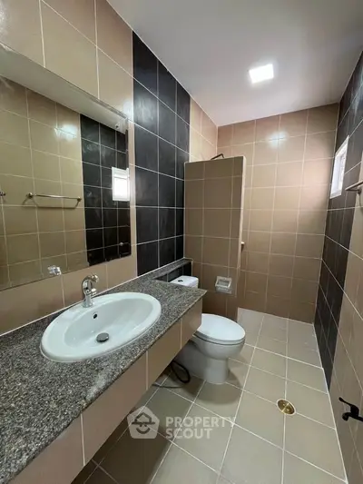 Modern bathroom with sleek design, featuring a granite countertop and stylish tile walls.