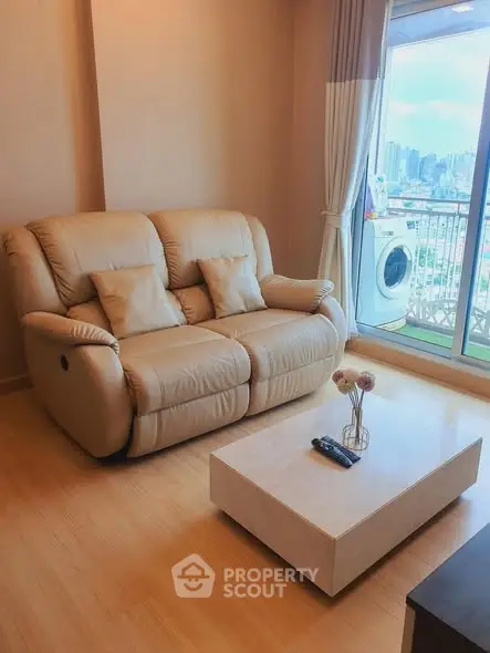 Cozy living room with beige sofa, coffee table, and balcony view with washing machine.
