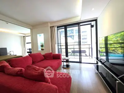Spacious living room with red sofas and large windows offering a bright view.