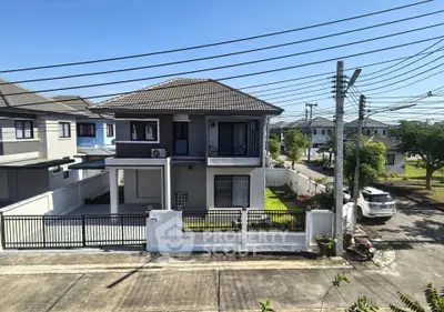 Modern two-story house with gated entrance and lush green lawn in suburban neighborhood.