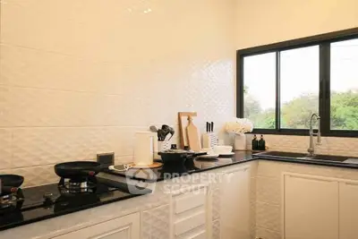 Modern kitchen with sleek design and large window offering natural light.