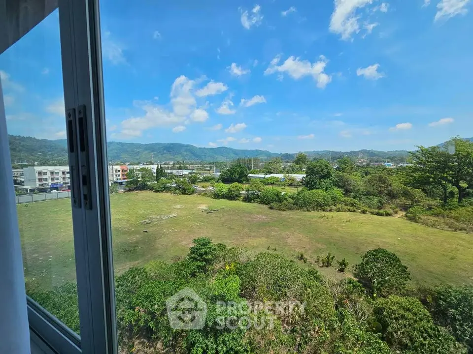 Stunning view from a window overlooking lush greenery and distant mountains, perfect for nature lovers.