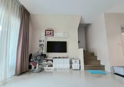 Modern living room with TV, fan, and staircase in stylish home