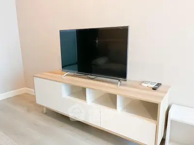Modern minimalist living room with sleek TV stand and large flat-screen TV, perfect for cozy family entertainment.
