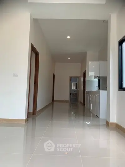 Modern hallway with glossy tiles and compact kitchen area, perfect for urban living.