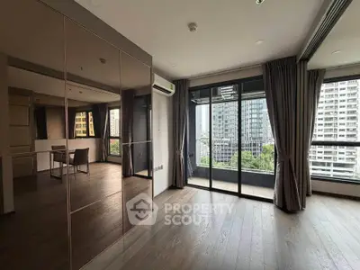 Spacious modern living room with large windows and city view, featuring elegant wooden flooring.