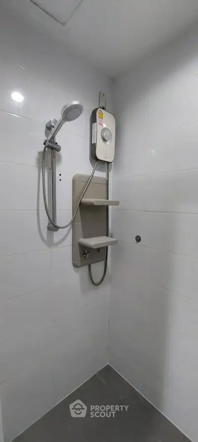 Modern bathroom shower with sleek white tiles and electric water heater.