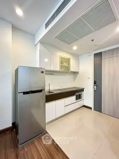 Modern kitchen with sleek cabinetry and stainless steel fridge in a contemporary apartment.