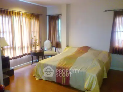 Cozy bedroom with large windows and elegant curtains, featuring a comfortable bed and stylish decor.