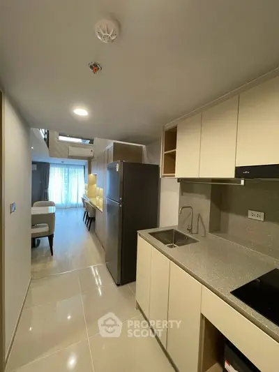 Modern kitchen with sleek cabinetry and open layout leading to a stylish living area.