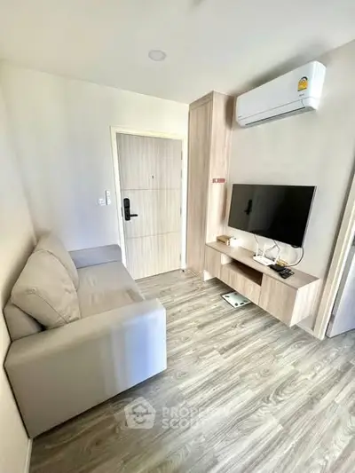 Modern living room with sleek furniture and wall-mounted TV in a cozy apartment.