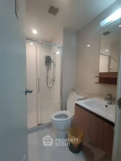 Modern bathroom with glass shower and sleek vanity in a contemporary apartment.