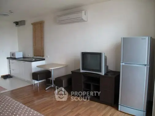 Modern studio apartment with kitchenette and cozy living area featuring air conditioning and hardwood floors.